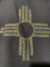 Load image into Gallery viewer, Black hoodie with yellow and clear rhinestone NM Zia symbol close up