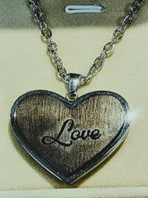 Load image into Gallery viewer, Heart-shaped pendant with 'Love' engraving on a chain, displayed against a neutral background.
